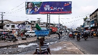 A woman walks past a campaign billboard for the President George Weah in Monrovia, Liberia