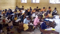 Some students in class on the bare floor writing