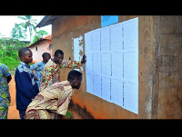 Voters look for their name on voter registration lists outside a polling station