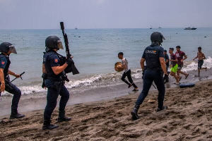 Spanish Guardia Civil officers stand guard as migrants cross from Morocco into the Spanish enclave