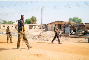 Soldiers patrol around burned homes, days after an attack in the village of Woro, Nigeria