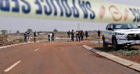 South African police and pathologists inspect the body of a woman found on the side of a road