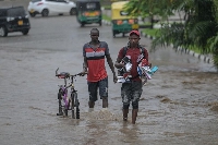Pedestrians walk in a flooded street in the town of Nyali, after heavy rainfall in Mombasa