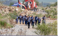 South African Police Service officers walk near the rescue operation to retrieve illegal miners