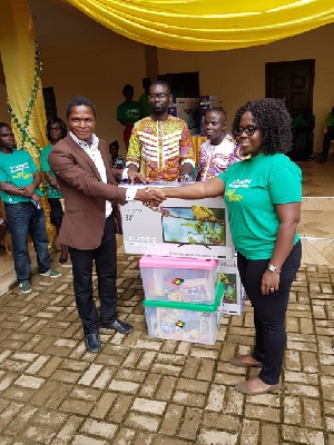 Mercy Quansah Ansah presenting the items to one of the teachers who assisted pupils to read
