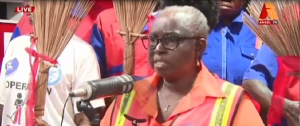 Workers are seen holding brooms during the protest while a woman voice out their concerns