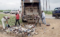 Members of the TMA task force collecting refuse into a truck along the Accra-Tema Motorway