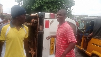 Two persons standing beside the somersaulted commercial car