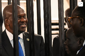 South Sudan’s suspended First Vice President Riek Machar stands inside a steel caged dock