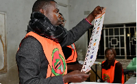 Election officials display a ballot paper while sorting and counting votes in Lusaka, Zambia