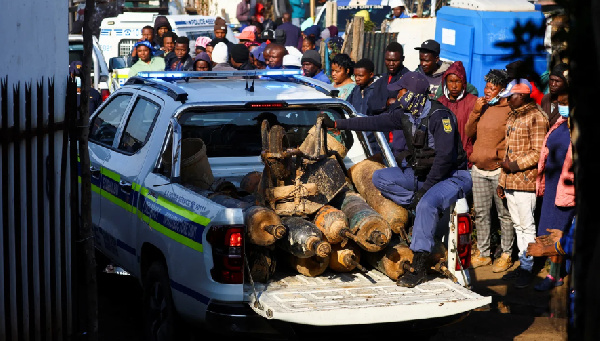 A police officer sits in the back of a police vehicle loaded with illegal mining equipment, after in