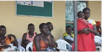 Women queue with their children at Kocgoma Health Centre III in Nwoya District