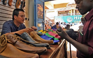 This picture shows an African buying shoes from a Chinese