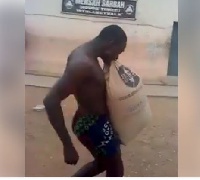Man carrying a bag of cement with his teeth