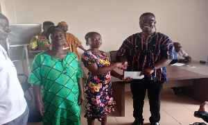 Ceaser Ofosu Acheampong, DCE, making the presentation to one of the beneficiaries