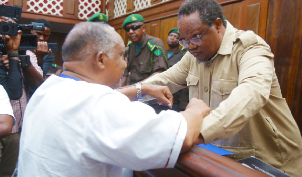 Tundu Lissu (in the dock) speaks with his brother, Alute Lissu, who is also a lawyer, in High Court