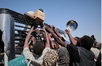 Sudanese families displaced from el-Fasher reach out as aid workers distribute food supplies