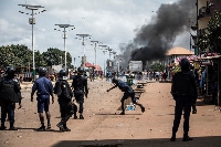 A police officer throws a stone at protesters, during a mass protest in Conakry in October 2020