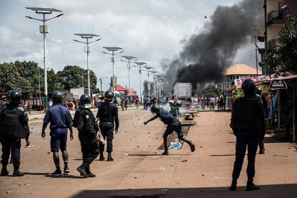 A police officer throws a stone at protesters, during a mass protest in Conakry in October 2020