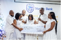 Eric Tsiri (with microphone) presenting the cheque to the parents of baby Jayden