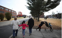 A refugee family walks past temporary housing