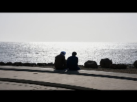 Two young men sitting on a beach in Dakar, Senegal