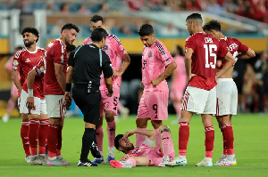 Messi, on the ground, surrounded by players during the game