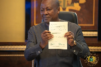 President John Dramani Mahama smiles as he shows the signed document to the public