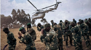 Soldiers protect their faces from projections when a helicopter lands in South Kivu Province