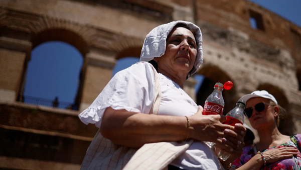 A woman queues to fill bottles with water near the Colosseum in Rome on July 11, 2023