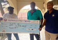 Some Alpha Lotto Executives presenting the cheque to Sellas Tetteh