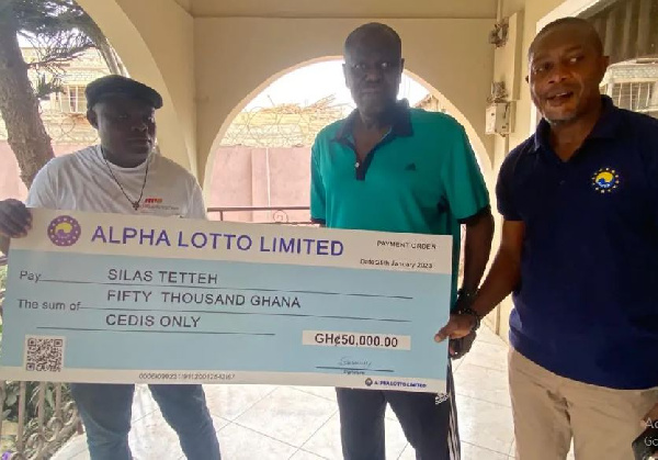 Some Alpha Lotto Executives presenting the cheque to Sellas Tetteh
