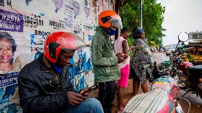 People using smartphones at a motorcycle taxis waiting area in Uganda