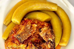 A bowl of garden egg stew served with boiled plantain