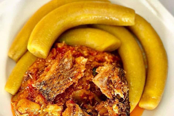 A bowl of garden egg stew served with boiled plantain