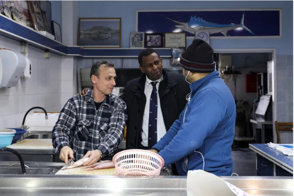 Hagabimana talks with two fishmongers on the island of Salamina [File: Louiza Vradi/Reuters]