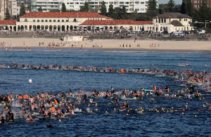 Surfers and swimmers congregate in the surf at Bondi Beach as they participate in a tribute