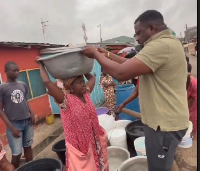 John Dumelo assisting a woman to carry water