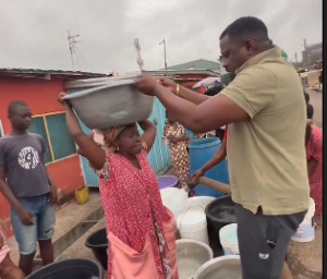 John Dumelo assisting a woman to carry water