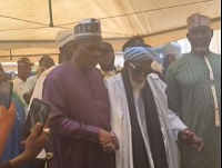 The Chief Imam (in white) stands at attention during the national anthem