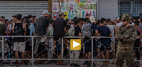 Migrants wait for a shop to open so they can buy food after crossing from Morocco into the Spanish