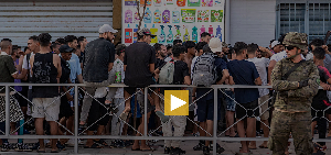 Migrants wait for a shop to open so they can buy food after crossing from Morocco into the Spanish