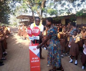 Male staff of EXP Ghana educating school kids on ways to cross the road and some traffic regulations