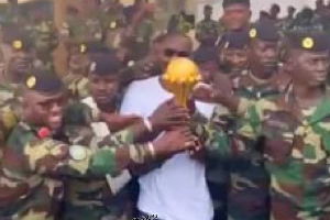 Pape Thiaw posing with the soldiers alongside the AFCON trophy
