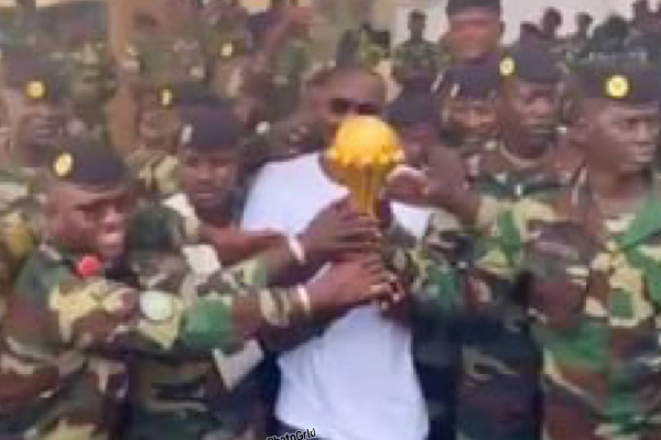 Pape Thiaw posing with the soldiers alongside the AFCON trophy
