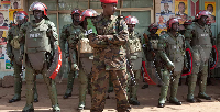 Armed military police stand guard as supporters of opposition leader Kizza Besigye, protest