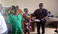DCE Ceaser Ofosu Acheampong making presentation to one of the beneficiaries