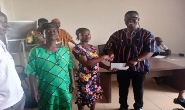 DCE Ceaser Ofosu Acheampong making presentation to one of the beneficiaries