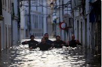 Volunteers wade through a flooded street after Storm Leonardo passed by Alcacer do Sal, Portugal