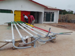 Emmanuel Boama (in red shirt) inspects manufactured streetlight poles